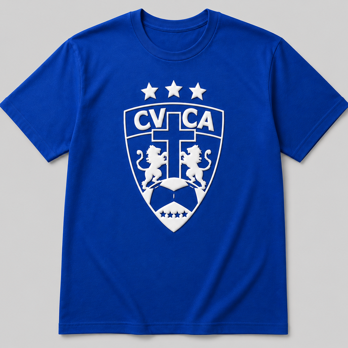 A royal blue short-sleeve t-shirt with a white printed shield crest featuring lions, stars, and the text 'CVCAC' on the chest, displayed against a neutral gray background.