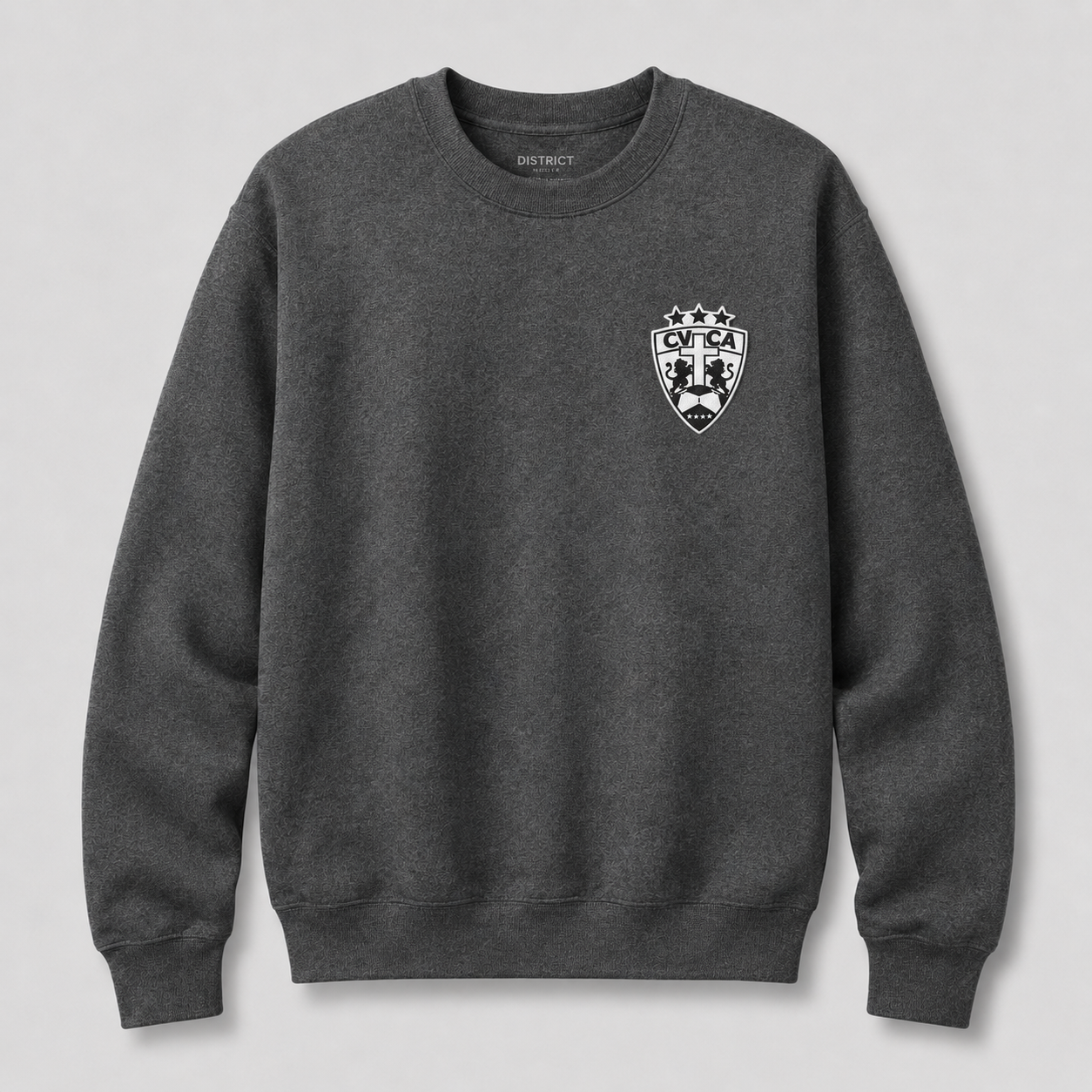 A dark heather gray crewneck sweatshirt with a white and black shield crest on the left chest, featuring the brand name 'DISTRICT' printed inside the collar, shown against a light gray background.